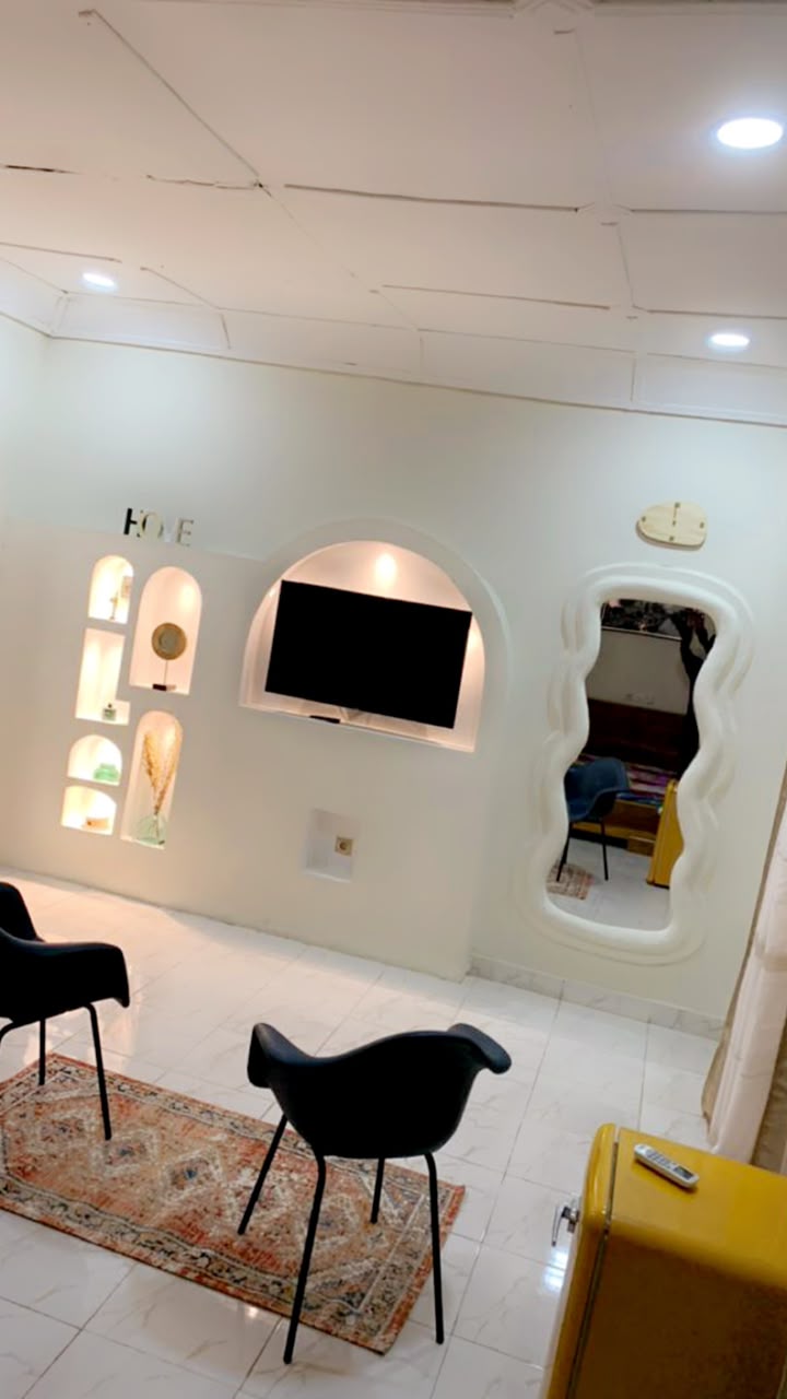 Pièce blanche avec niches éclairées et miroir aux contours ondulés